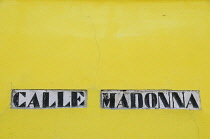 Italy, Veneto, Venice, Burano, Calle Madonna street sign on yellow wall.