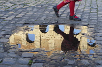 Italy, Lazio, Rome, Colosseum, girl running past puddle with reflection of the Colosseum.