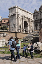 Italy, Lazio, Rome, Roman Forum, Foro Romano, Arch of Septimus Severus with family walking along cobbled road.