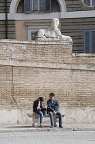Italy, Lazio, Rome, Northern Rome, Piazza del Popolo, Sphinx statue & people reading in the square.