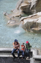 Italy, Lazio, Rome, Centro Storico, Trevi Fountain, family throwing coins into fountain.