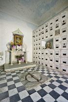 Italy, Liguria, Cinque Terre, Manarola, An indoor section of the town cemetery above the town on Punta Bonfiglio with marble walls of niches wherein people are buried and a small decorated altar.