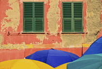 Italy, Liguria, Cinque Terre,  Vernazza, Colourful beach umbrellas in front of traditional shuttered windows at the townâ��s harbour.