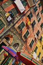 Italy, Liguria, Cinque Terre,  Vernazza, Colourful beach umbrellas in front of traditional shuttered apartments at the townâs harbour with clothes hanging out to dry.