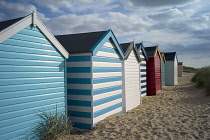 England, Suffolk, Southwold, Group of brightly coloured beach huts near Gun Hill.