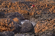 Ireland, County Antrim, Giants Causeway, a tourist sitting among the rocks admiring the view.