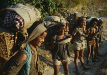Nepal, Near Mongmaya, Row of porters loaded with baskets on their backs.