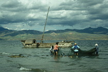 China, Yunnan, Dali, Fishermen dragging nets by the moored boatside.