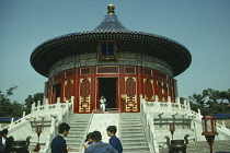 China, Beijing, Temple of Heaven, Round altar with woman walking down the steps from the entrance and group gathered in the foreground.