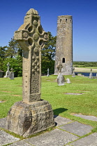 Ireland, County Offaly, Clonmacnoise Monastic Settlement, Replica of the South Cross with Round Tower in the background.