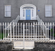 Ireland, County Offaly, Birr which is a town renowned for its Georgian architecture, John's Mall, elegant light blue Georgian doorway with steps leading up to it and an ornamental white railing gate.