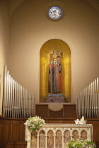 Italy, Tuscany, Lucca, Barga, Interior of church with statue, altar and organ pipes visible.