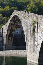 Italy, Tuscany, Lucca, Garfagnana, Bagni di Lucca, Devil's aka Maddalena's Bridge with people walking over the high arch