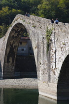 Italy, Tuscany, Lucca, Garfagnana, Bagni di Lucca, Devil's aka Maddalena's Bridge with people walking over the high arch