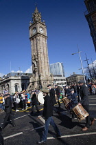 Ireland, North, Belfast, St Patricks Day parade passing the Albert clock on the corner of High Street and Victoria Street.