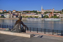 Hungary, Budapest, View across the Danube to Castle Hill with a statue of the Hungarian poet Jozsef Attila in the foreground.