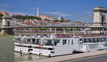 Hungary, Budapest, View across the River Danube to Castle Hill with the Chain Bridge and boats in the foreground.