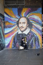 England, London, Southwark, Tuba playing busker in front of William Shakespeare mural under railway arch near Borough Market