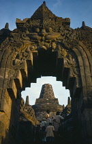 Indonesia, Java, Borobudur, Part view of Buddhist stupa framed in carved archway with visitors.