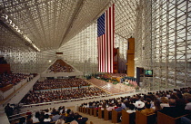 USA, California, Los Angeles, Interior view of Crystal Cathedral on Memorial Day with people sittting in stands surrounding the American flag.
