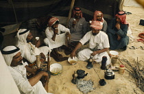 Bahrain, Bedouin men eating together in tent.