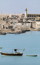 Qatar, Khor, The fishing harbour with boats at anchor and the town with a mosque minaret beyond.