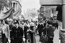 England, London, Gay Pride Parade, Strand, 1979, June 30, beside South African High Commission, parade, banners, Metropolitan Police escort, pedestrains, Press photographer, Black policeman.