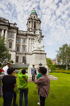 Ireland, North, Belfast, Tourists photographing the Titanic memorial in the grounds of the City Hall.