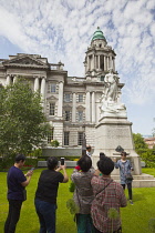 Ireland, North, Belfast, Tourists photographing the Titanic memorial in the grounds of the City Hall.