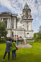 Ireland, North, Belfast, Tourists photographing the Titanic memorial in the grounds of the City Hall.