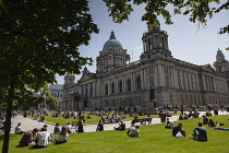 Ireland, North, Belfast, Tourists and office workers relaxing on city hall lawns during lunchtime.