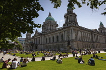 Ireland, North, Belfast, Tourists and office workers relaxing on city hall lawns during lunchtime.