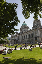 Ireland, North, Belfast, Tourists and office workers relaxing on city hall lawns during lunchtime.