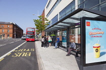 Ireland, North, Belfast, Titanic Quarter, Tourists at bus stop awaiting tour bus.