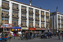 Pedicabs wait in front of modern apartments with traditional designs in Lhasa, Tibet.