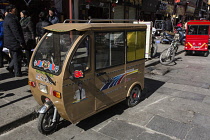 A tiny passenger van, like an enclosed tuk-tuk or autorickshaw, in Lhasa, Tibet.