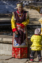A Tibetan woman in festive dress for a photograph wih her child in Lhasa, Tibet.