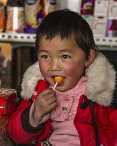 A young Tibetan child enjoys a piece of candy in Lhasa, Tibet.
