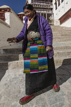 A Khamba Tibetan woman from the Kham region of eastern Tibet on a pilgrimage to visit holy sites in Lhasa, Tibet.  She is wearing her colorful traditional bangdian or pangden apron.