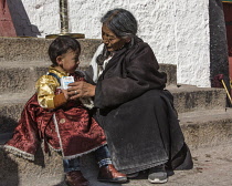 A Khamba grandmother helps her grandson during a pilgrimage to the Potala Palace in Lhasa, Tibet.  The Khamba people are from the Kham region of eastern Tibet.