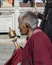 A Tibetan Buddhist nun with her prayer wheel takes a rest while circumambulating  the Potala Palace in Lhasa, Tibet.