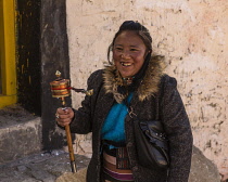 An young Tibetan woman pilgrim with her prayer wheel at the Drepung Monastery near Lhasa, Tibet.