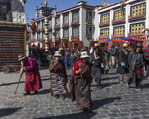 Older Tibetan women in traditional dress circumambulate the Jokhang Temple with their pray wheels in Lhasa, Tibet.