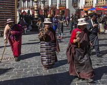 Older Tibetan women in traditional dress circumambulate the Jokhang Temple with their pray wheels in Lhasa, Tibet.