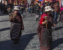 Older Tibetan women in traditional dress circumambulate the Jokhang Temple with their pray wheels in Lhasa, Tibet.