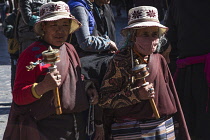 Older Tibetan women in traditional dress circumambulate the Jokhang Temple with their pray wheels in Lhasa, Tibet.