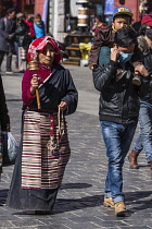 Tibetan Buddhist pilgrims from the Kham region of eastern Tibet circumambulating around the Jokhang Temple in Lhasa, Tibet.  The woman is wearing her pangden apron and carries her mala rosary beads an...