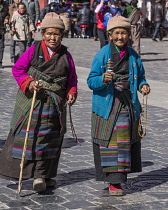 Older Tibetan women in traditional dress circumambulate the Jokhang Temple with their prayer wheels in Lhasa, Tibet.