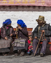 Tibetan Buddhist pilgrims from the Kham region of eastern Tibet circumambulating around the Jokhang Temple in Lhasa, Tibet.  The man wears the traditional golden thread hat and the women wear their pa...