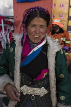 A Khamba Tibetan woman from the Kham region of eastern Tibet on a pilgrimage to visit holy sites in Lhasa, Tibet.  She is wearing a traditional heavy sheepskin-lined chupa or chuba coat.